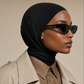 Micro Hijab in Schwarz, Profilaufnahme mit Sonnenbrille und beigem Trenchcoat über brauner Bluse. KI-generiertes Bild.