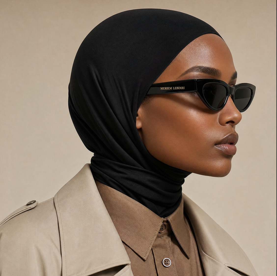 Micro Hijab in Schwarz, Profilaufnahme mit Sonnenbrille und beigem Trenchcoat über brauner Bluse. KI-generiertes Bild.