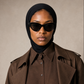 Micro Hijab in Schwarz, Nahaufnahme mit schwarzer Sonnenbrille und braunem Trenchcoat. KI-generiertes Bild.