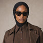 Micro Hijab in schwarz, Nahaufnahme mit Schildpatt-Sonnenbrille, seitlicher Blick, brauner Trenchcoat. KI-generiertes Video.